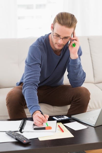 A person sitting at a desk, reviewing financial documents and using a calculator, symbolizing the careful consideration needed before refinancing a mortgage.