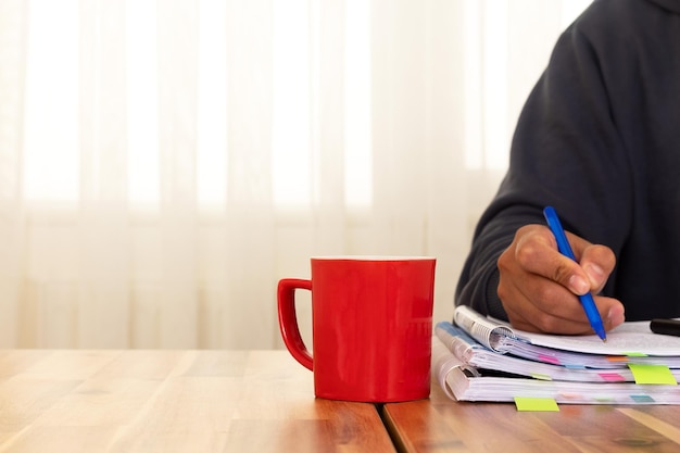 A person reviewing several documents related to employee benefits on a desk with a laptop and coffee mug, emphasizing the importance of research and preparation.