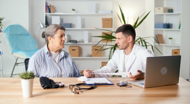 A financial advisor sitting across a desk from a client, explaining a disability insurance policy document. The advisor points to a specific clause in the document, while the client listens attentively. Bright, professional office setting.