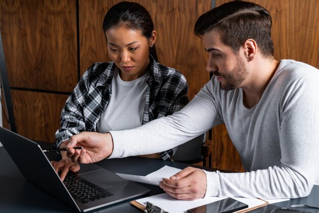 A college administrator assisting a student with enrolling in a tuition payment plan on a computer. The setting is a financial aid office, indicating official support.