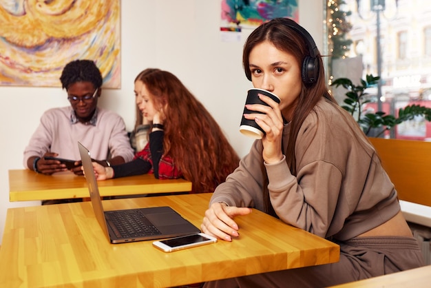 A student is using a laptop in a coffee shop, surrounded by notebooks and planners, with a determined expression, showcasing the active planning process for a successful gap year.