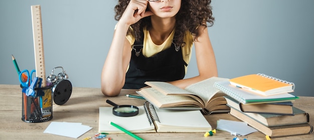 A student sitting at a desk, surrounded by books and papers, looking thoughtful and focused. The student is using a laptop and a planner to organize their coursework and study schedule.
