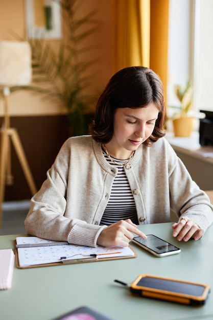 A student sitting at a desk, filling out a college application form, with a calculator and financial documents nearby. The setting suggests a focus on affordability and planning.